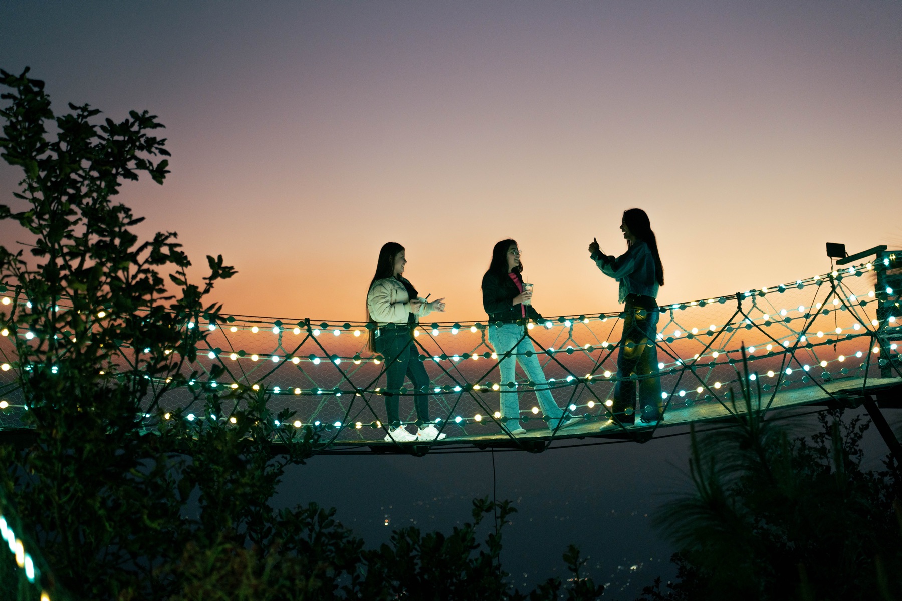 Visitantes sobre el puente iluminado de Xwan al atardecer